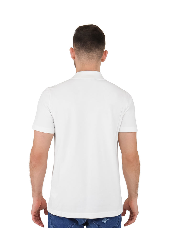 Hombre vistiendo polo Lacoste blanco con franja azul celeste y letras grandes en el pecho