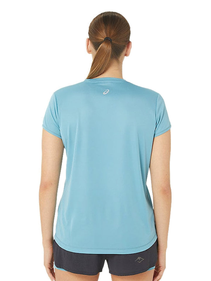 Mujer vistiendo camiseta deportiva ASICS de color azul grisáceo con logo en el pecho y shorts oscuros.
