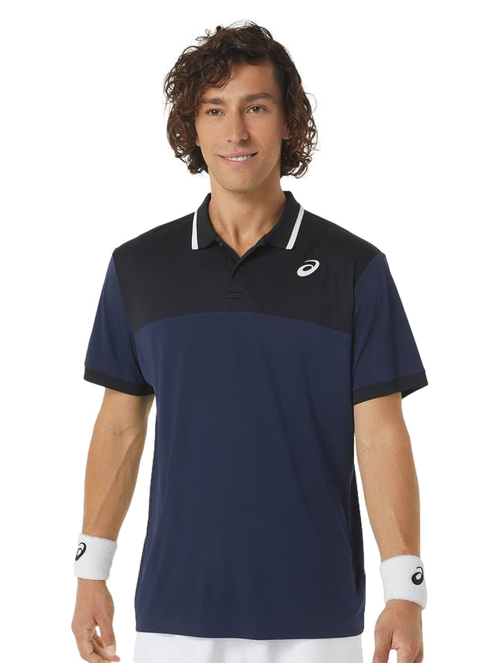 Hombre vistiendo polo deportiva ASICS en colores azul marino y negro con detalles blancos en el cuello.