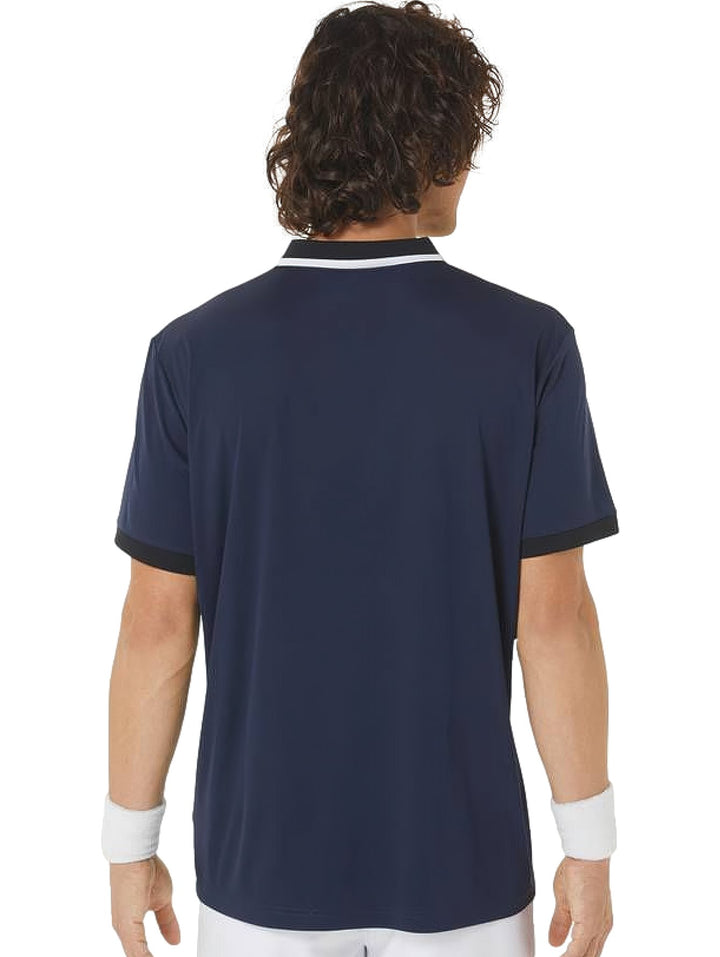 Hombre vistiendo polo deportiva ASICS en colores azul marino y negro con detalles blancos en el cuello.
