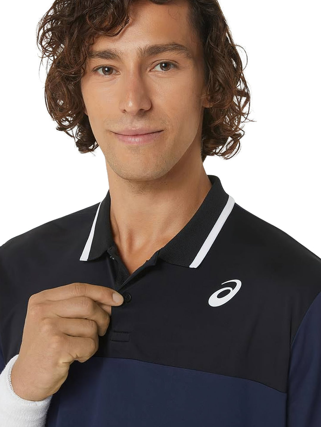 Hombre vistiendo polo deportiva ASICS en colores azul marino y negro con detalles blancos en el cuello.