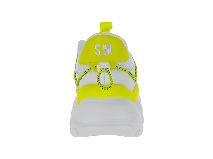 Tenis deportivos blancos con detalles en amarillo neón y suela gruesa de la marca Steve Madden.