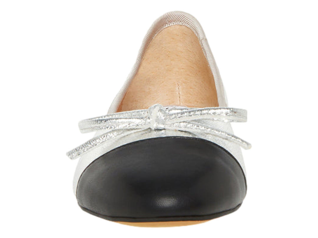Zapato plano color plata metálico con punta negra y detalle decorativo superior.