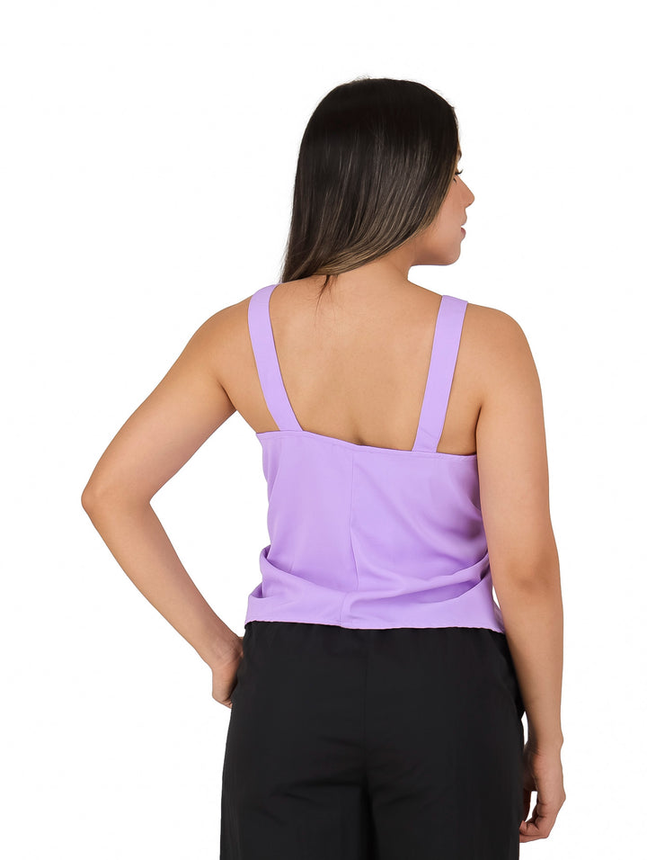 Mujer vistiendo blusa lila sin mangas con detalle de amarre frontal y pantalones negros.