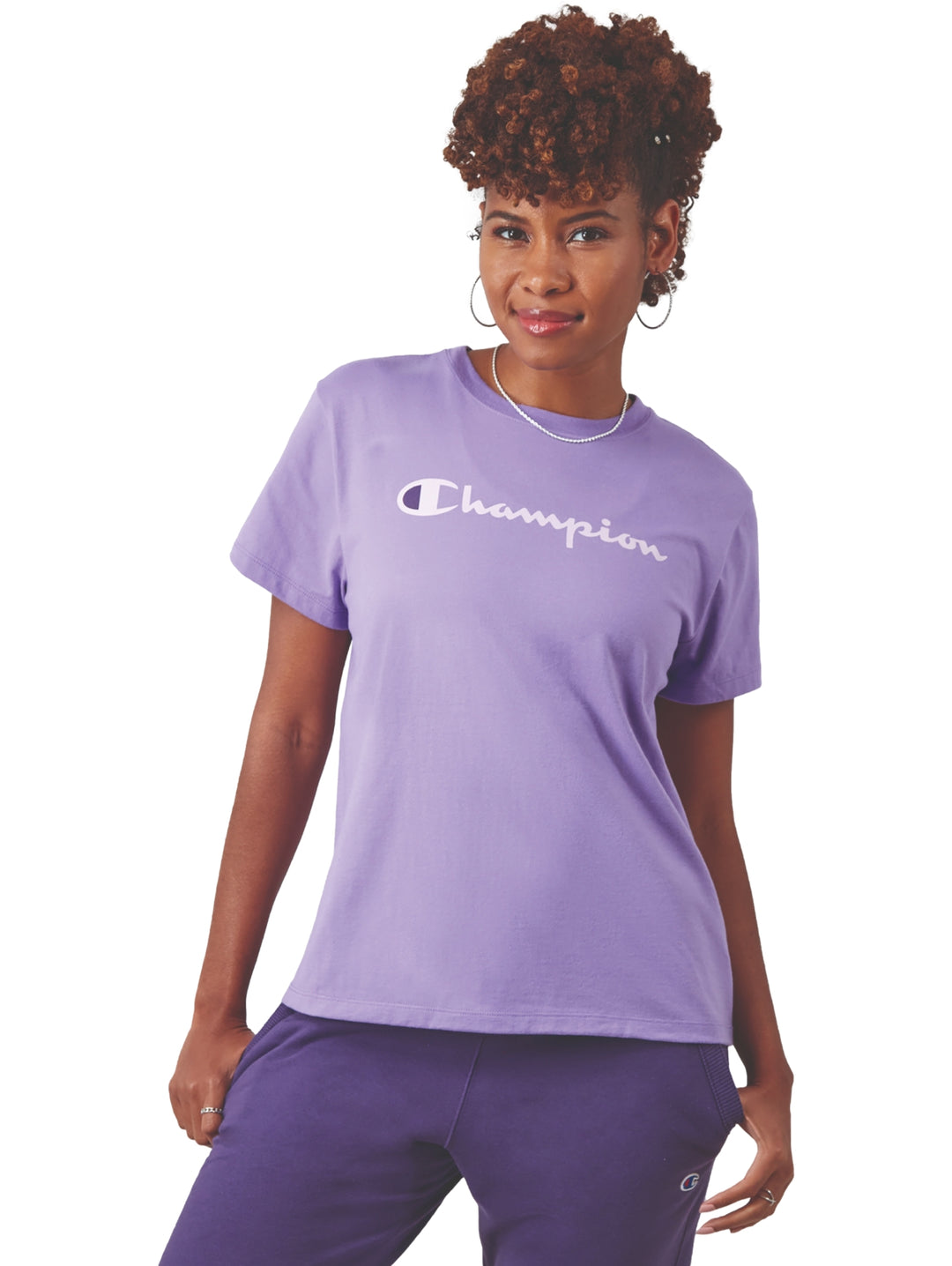 Mujer vistiendo una camiseta Champion color lavanda y pantalones deportivos morados.