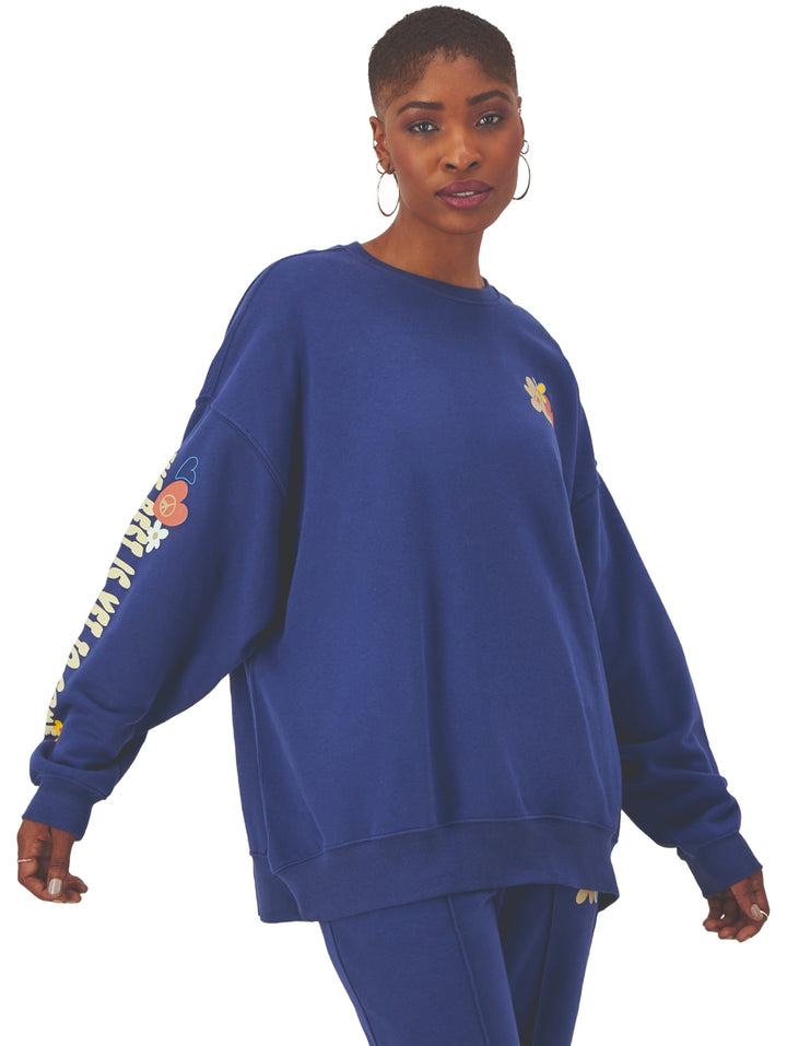 Mujer vistiendo sudadera Champion azul blown glass blue de corte oversized con estampado en la manga.