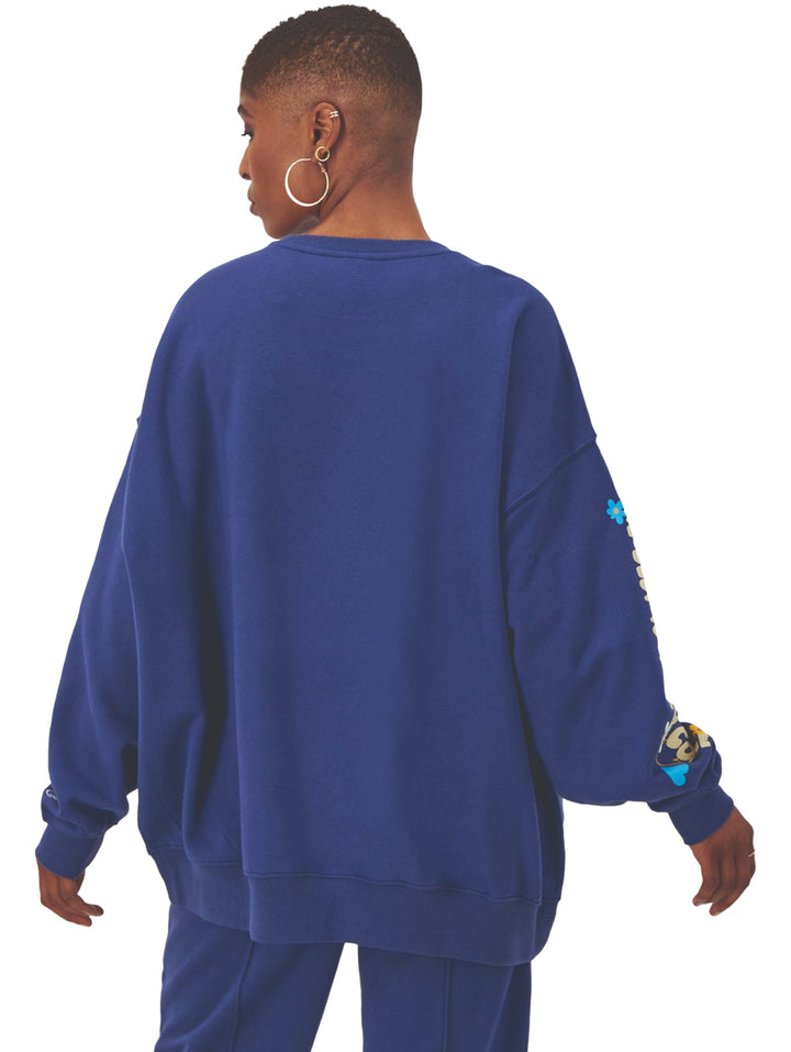 Mujer vistiendo sudadera Champion azul blown glass blue de corte oversized con estampado en la manga.