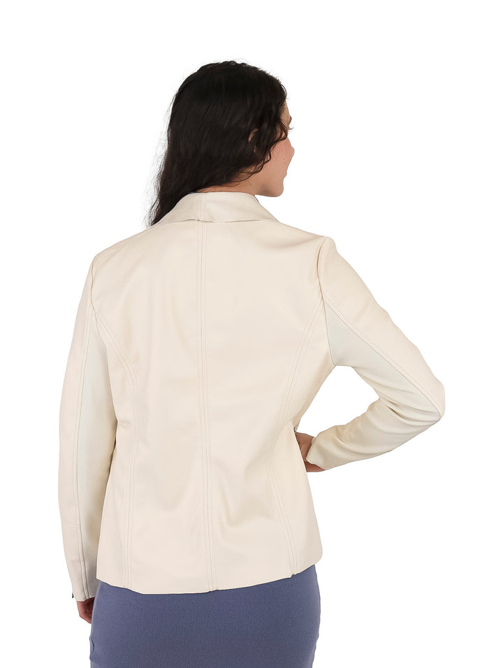 Mujer modelando una chaqueta beige de material sintético abierta sobre un vestido azul.