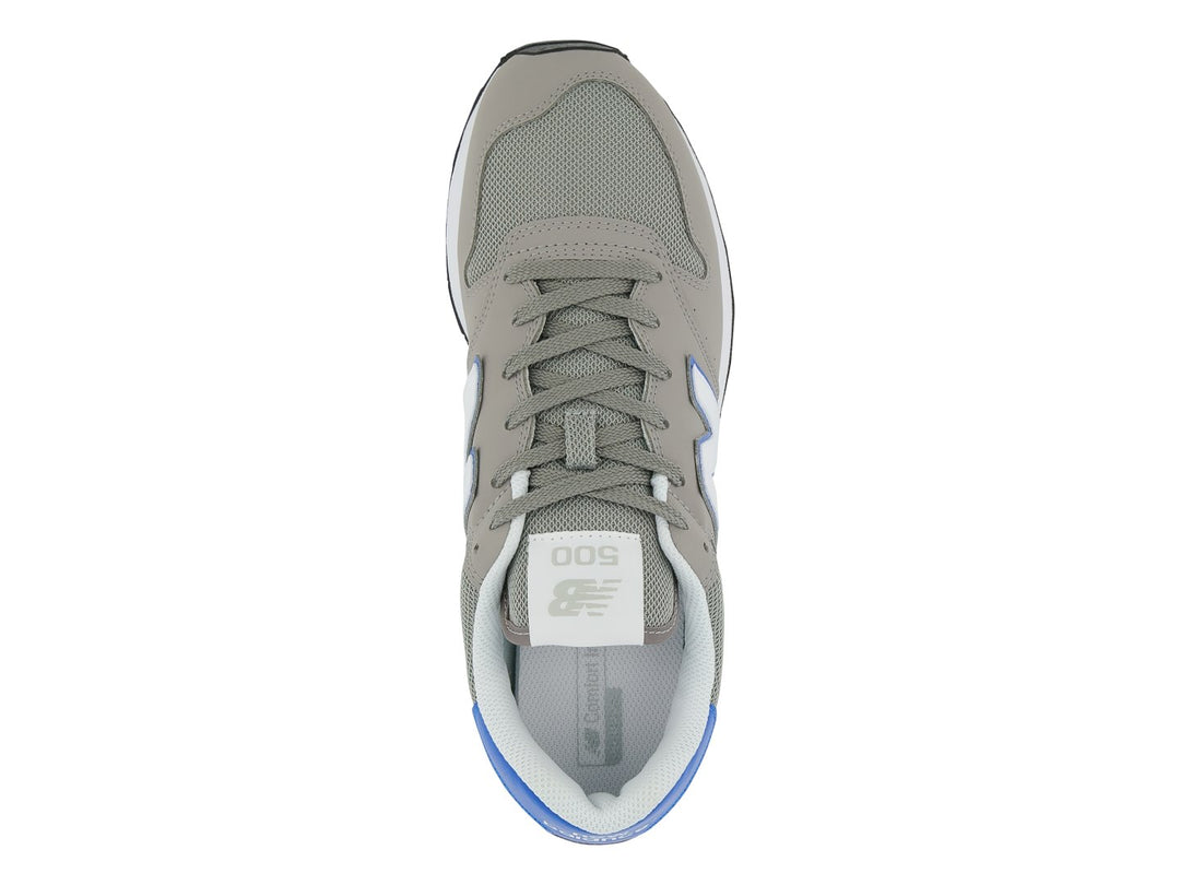 Tenis New Balance color gris con detalles en azul, suela blanca y negra.