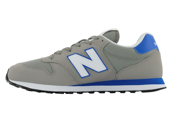 Tenis New Balance color gris con detalles en azul, suela blanca y negra.