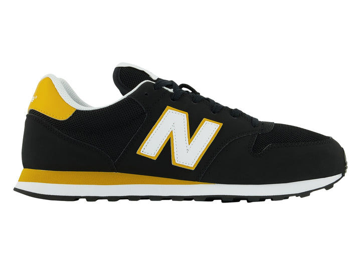 Tenis New Balance modelo GM500V en color negro con detalles en amarillo y blanco.