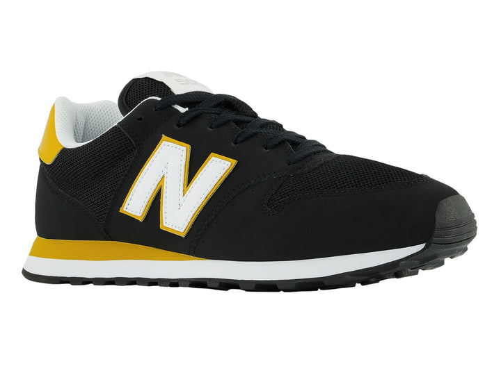 Tenis New Balance modelo GM500V en color negro con detalles en amarillo y blanco.