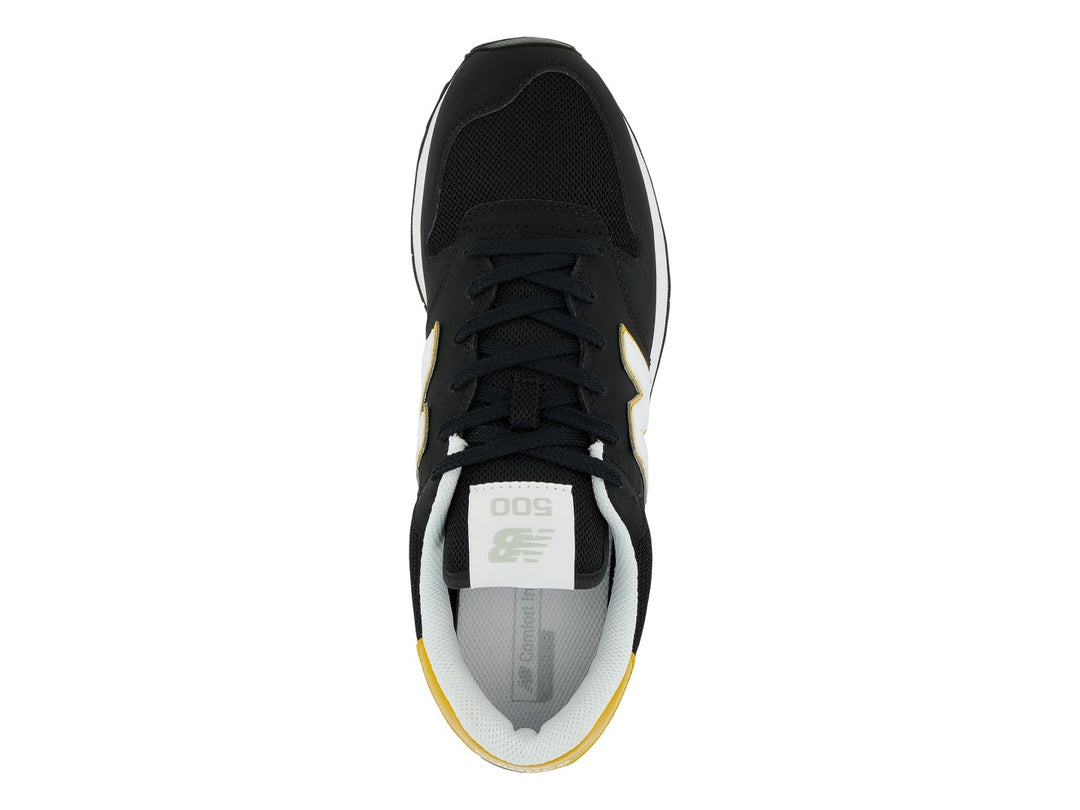 Tenis New Balance modelo GM500V en color negro con detalles en amarillo y blanco.