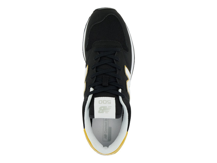Tenis New Balance modelo GM500V en color negro con detalles en amarillo y blanco.
