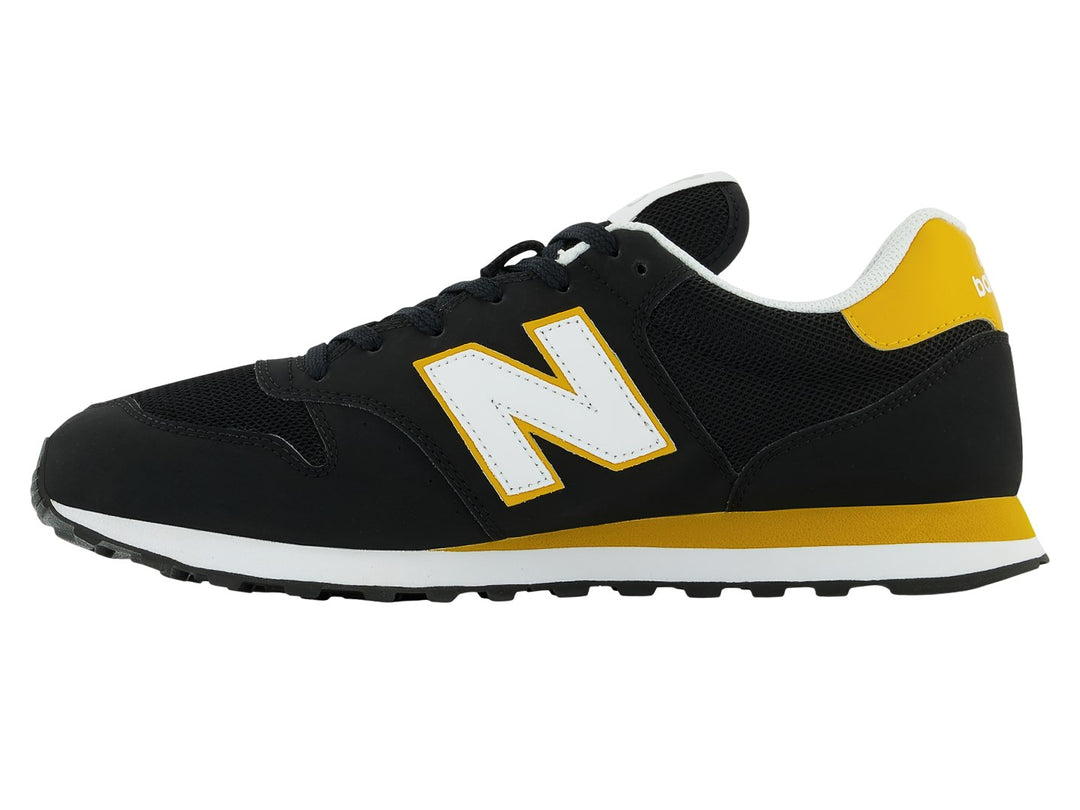 Tenis New Balance modelo GM500V en color negro con detalles en amarillo y blanco.