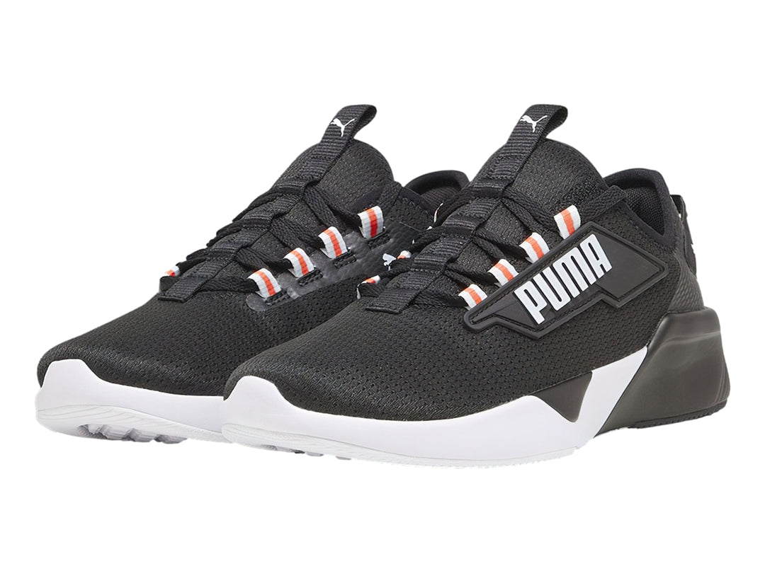 Tenis deportivos PUMA color negro con suela blanca y detalles naranjas en los ojales.
