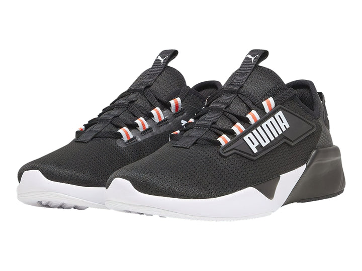 Tenis deportivos PUMA color negro con suela blanca y detalles naranjas en los ojales.