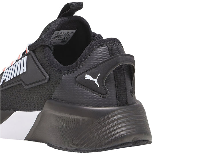 Tenis deportivos PUMA color negro con suela blanca y detalles naranjas en los ojales.