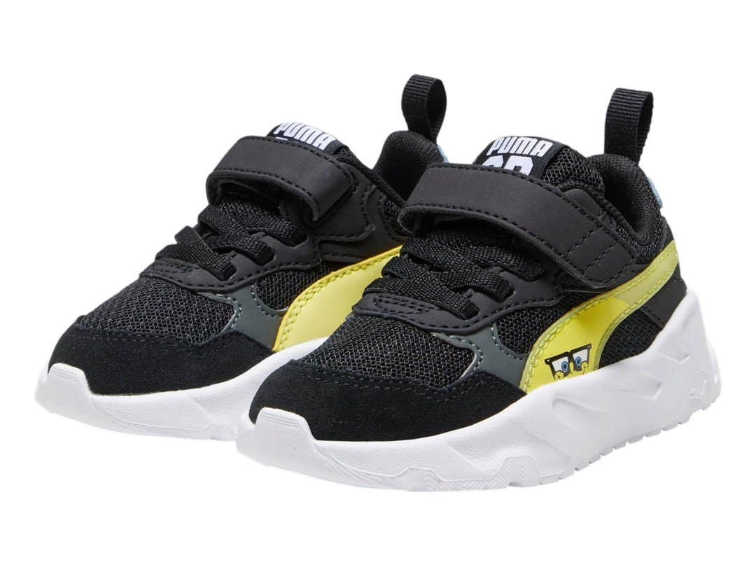 Tenis PUMA infantiles color negro con franja amarilla y suela blanca gruesa.