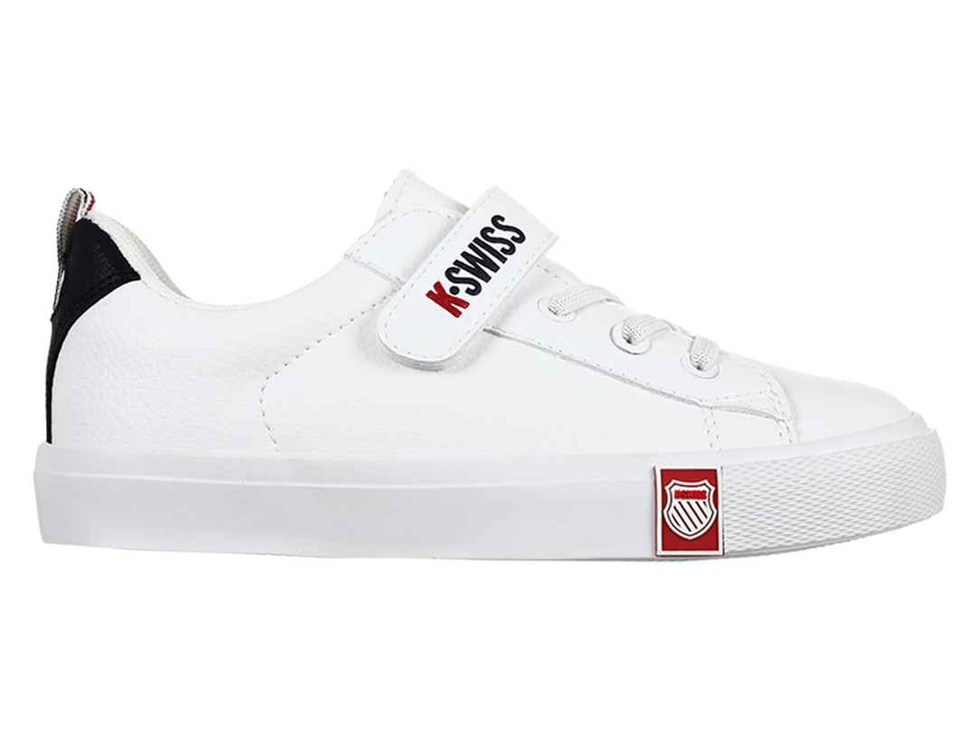Tenis K-Swiss blancos para niño con cierre de velcro y detalle azul marino en el talón.