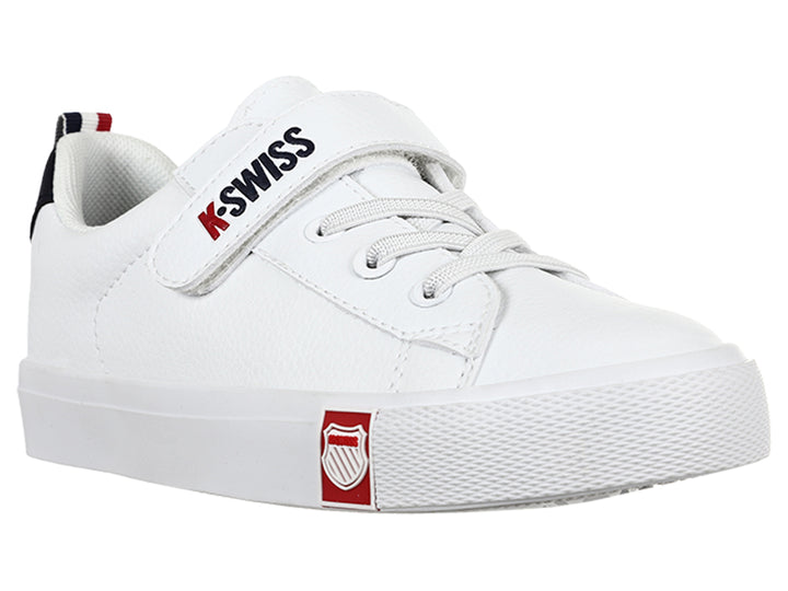 Tenis K-Swiss blancos para niño con cierre de velcro y detalle azul marino en el talón.