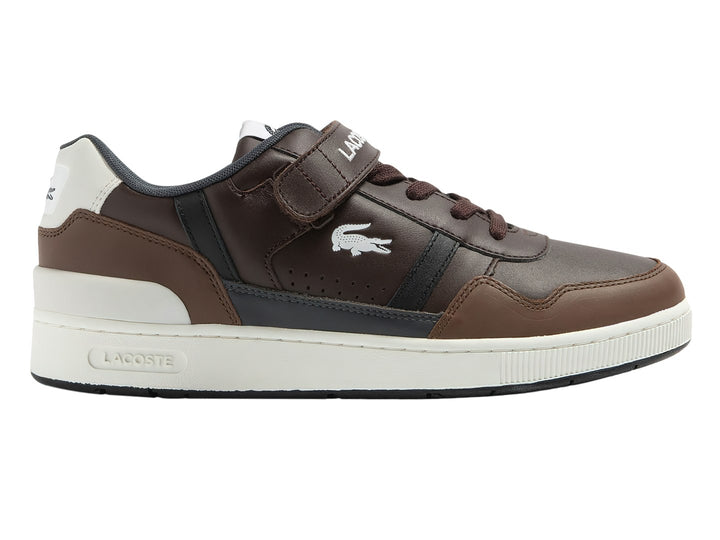Tenis Lacoste color marrón oscuro con suela blanca y correa de velcro.