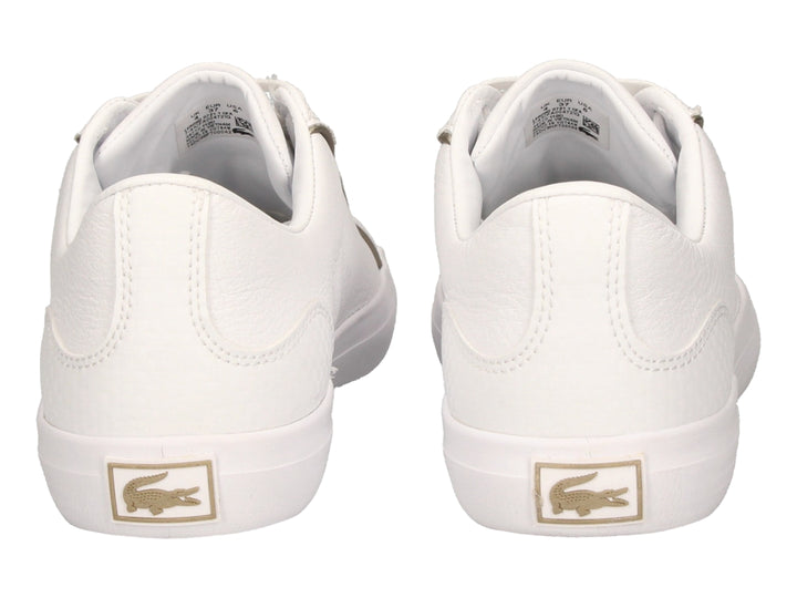 Tenis blancos de cuero marca Lacoste con cordones y logo del cocodrilo en el costado.