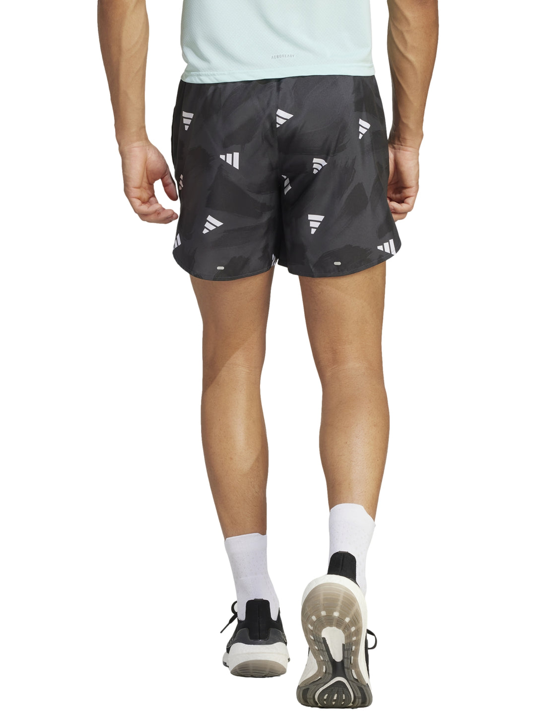 Hombre vistiendo shorts deportivos Adidas color negro con estampado de logos blancos.