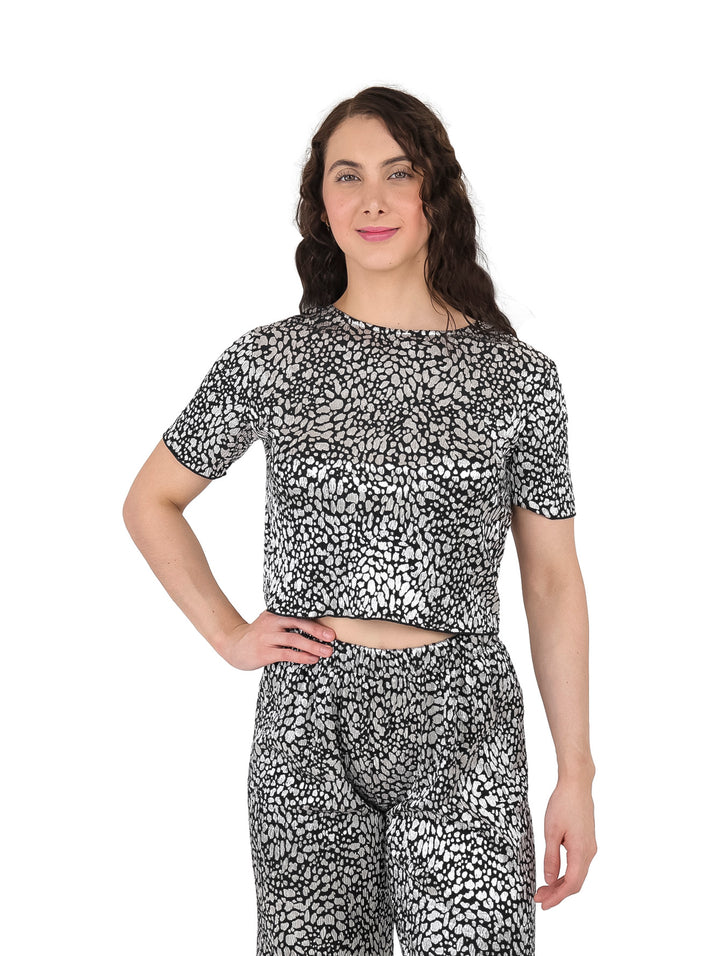 Mujer vistiendo blusa de manga corta con estampado abstracto en color plata y negro brillante.