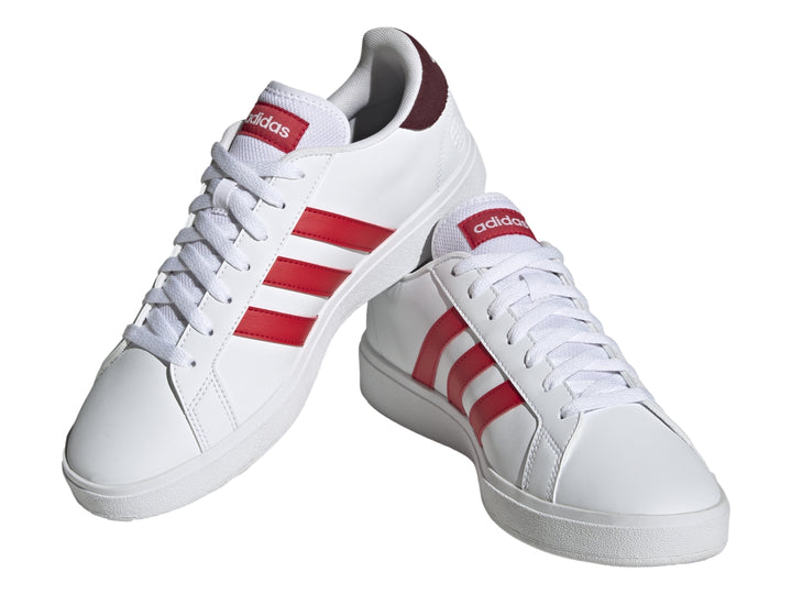 Tenis Adidas blancos con tres franjas rojas laterales y detalle en el talón en color rojo oscuro.