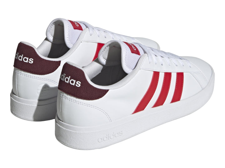 Tenis Adidas blancos con tres franjas rojas laterales y detalle en el talón en color rojo oscuro.
