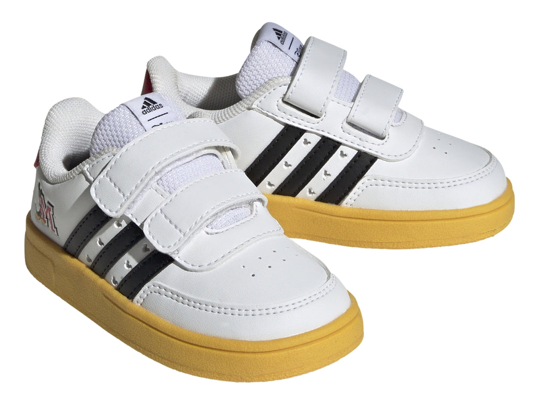 Tenis blancos Adidas para niño con suela amarilla, franjas negras y diseño de Mickey Mouse con cierres de velcro.