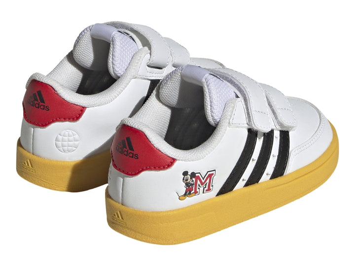 Tenis blancos Adidas para niño con suela amarilla, franjas negras y diseño de Mickey Mouse con cierres de velcro.