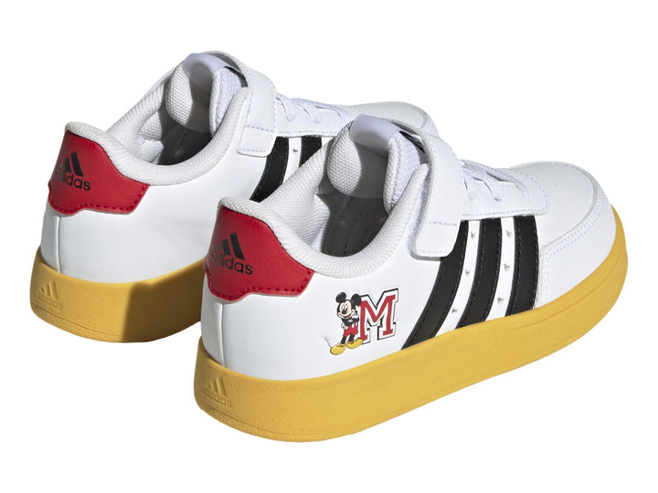 Tenis Adidas blancos con suela amarilla, franjas negras y gráfico de Mickey Mouse.