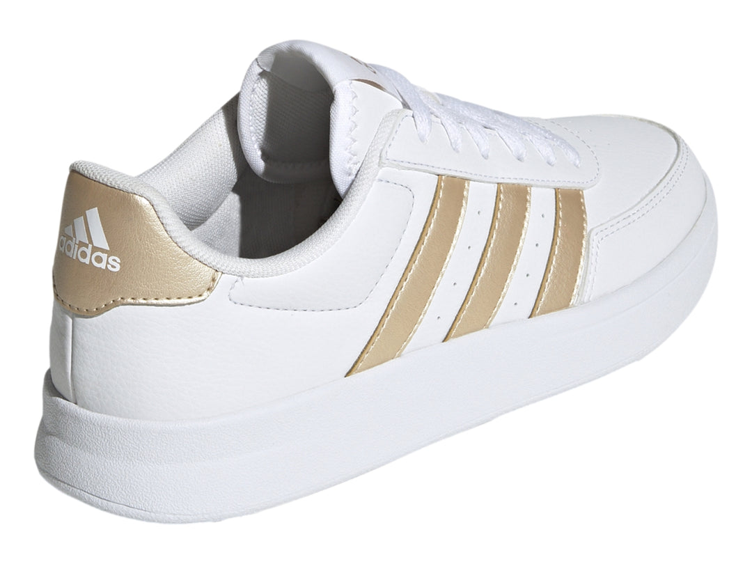 Tenis Adidas blancos con franjas laterales y detalle en el talón en color dorado.