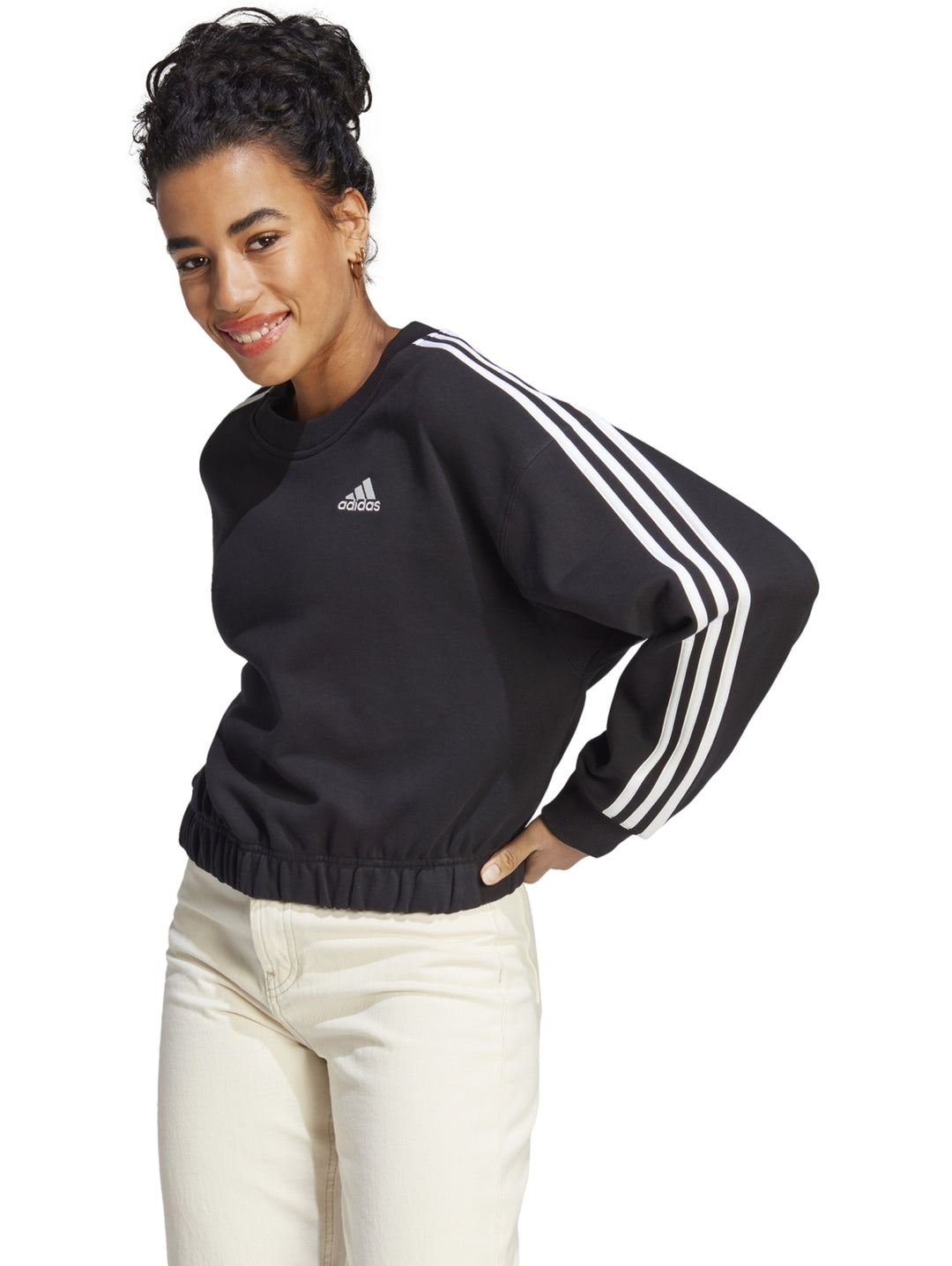 Mujer vistiendo sudadera corta negra Adidas con tres rayas blancas en las mangas.