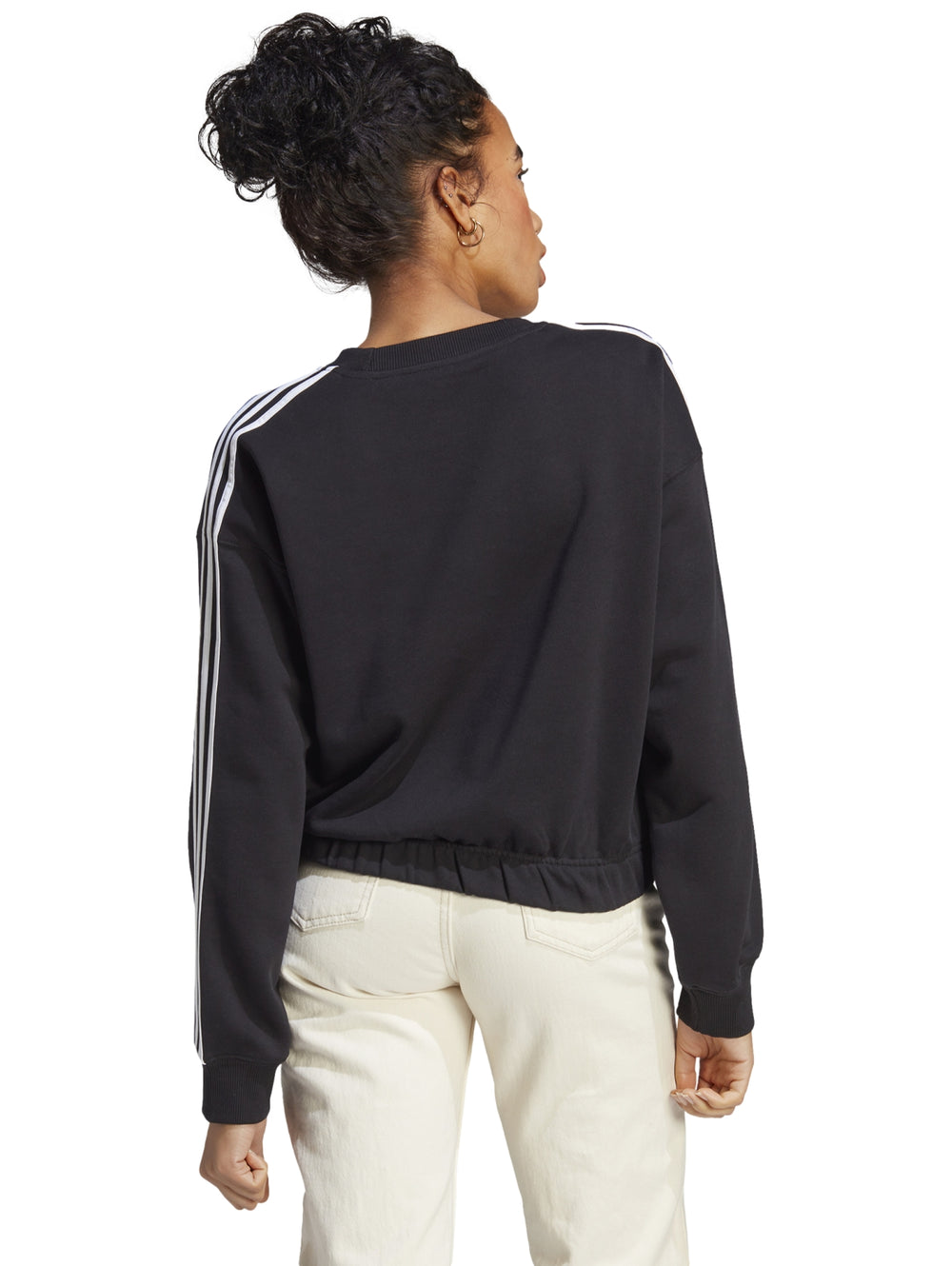 Mujer vistiendo sudadera corta negra Adidas con tres rayas blancas en las mangas.