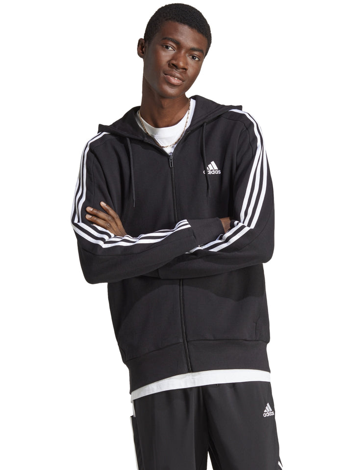 Hombre vistiendo sudadera deportiva Adidas color negro con rayas blancas en las mangas y capucha.
