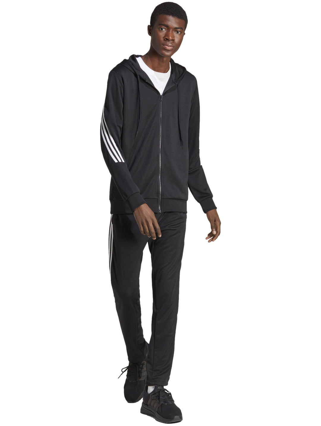 Hombre vistiendo un conjunto deportivo Adidas negro con rayas blancas laterales y capucha.