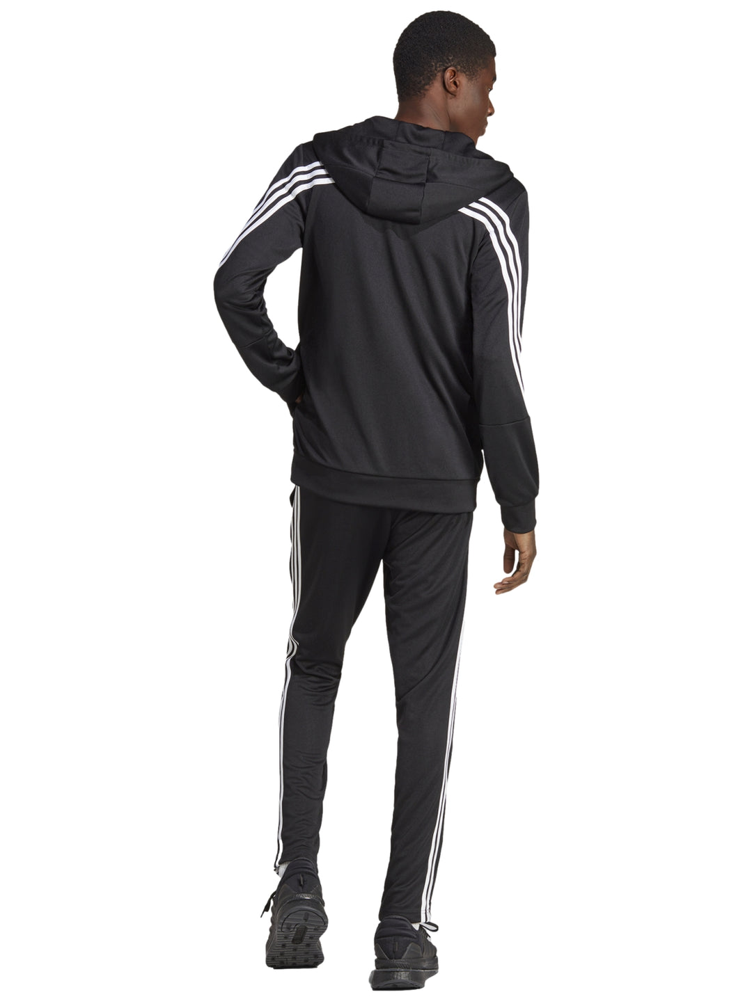 Hombre vistiendo un conjunto deportivo Adidas negro con rayas blancas laterales y capucha.