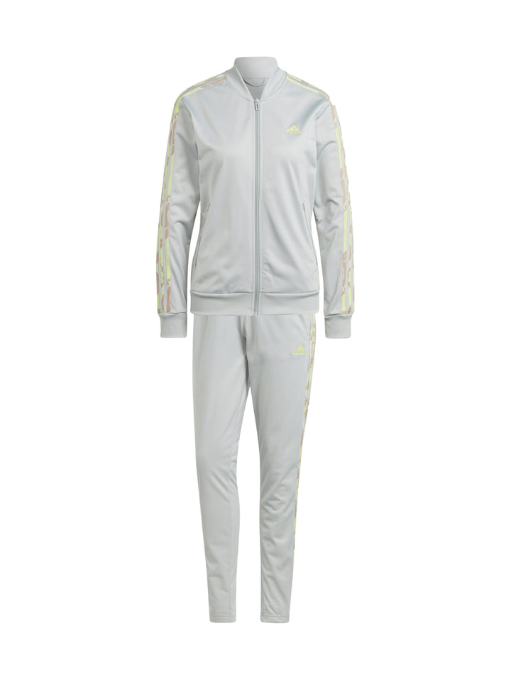 Mujer vistiendo pantalones deportivos Adidas color plata con franjas laterales multicolores.