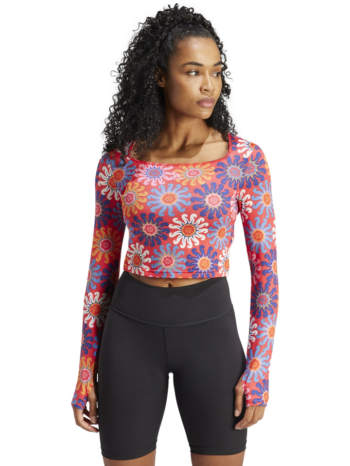 Mujer vistiendo un crop top deportivo de manga larga con estampado floral multicolor.