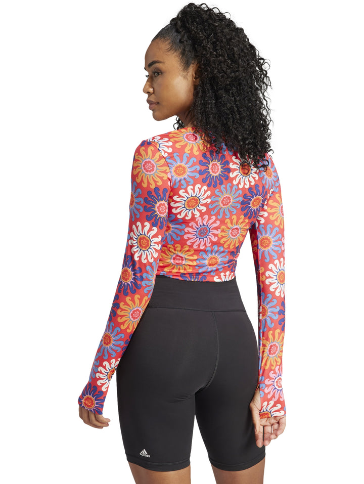 Mujer vistiendo un crop top deportivo de manga larga con estampado floral multicolor.