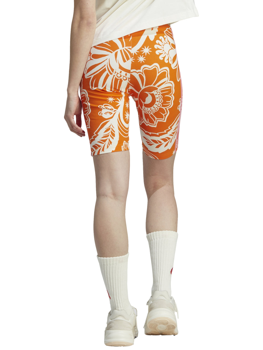 Shorts deportivos Adidas color naranja con estampado floral blanco y rayas laterales blancas.