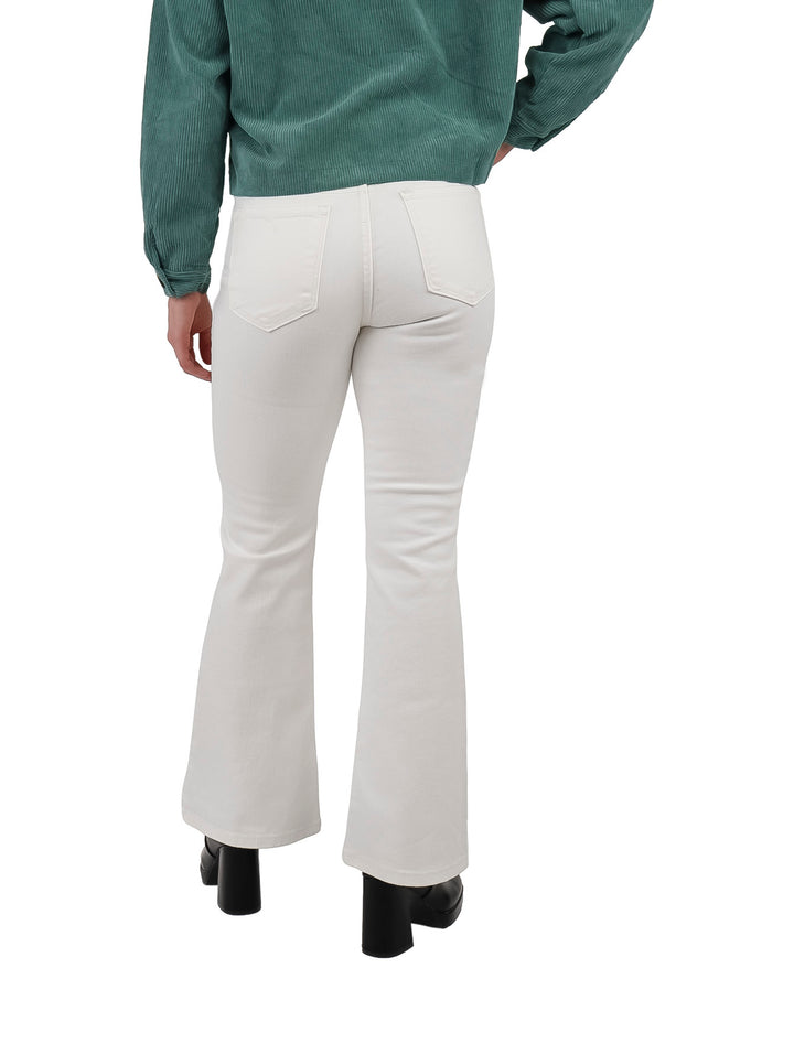 Mujer vistiendo jeans blancos de corte campana con zapatos negros sobre fondo blanco.