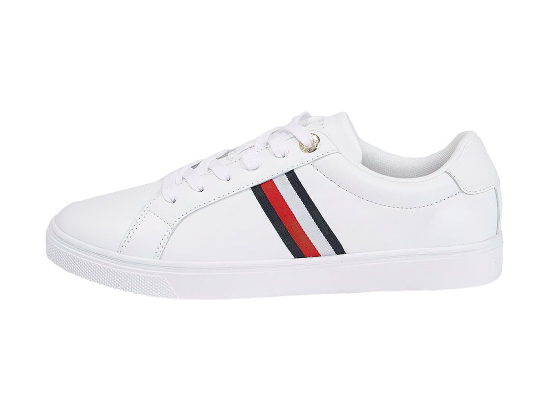 Tenis Tommy Hilfiger blancos con franjas azul y roja en el lateral y suela blanca.