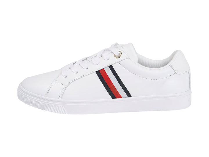 Tenis Tommy Hilfiger blancos con franjas azul y roja en el lateral y suela blanca.