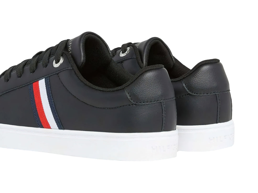 Tenis Tommy Hilfiger color negro con suela blanca y franjas laterales en rojo, blanco y azul.
