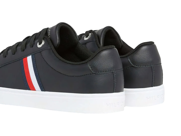 Tenis Tommy Hilfiger color negro con suela blanca y franjas laterales en rojo, blanco y azul.