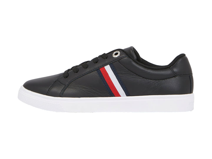 Tenis Tommy Hilfiger color negro con suela blanca y franjas laterales en rojo, blanco y azul.